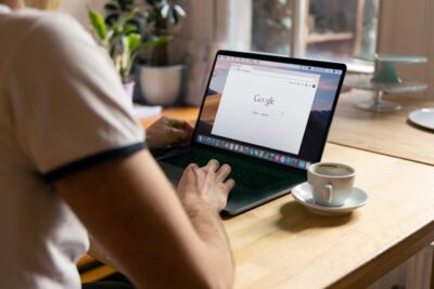 Man uses Apple MacBook in a cafe or restaurant. He is searching Google website