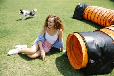 woman sitting on green lawn near playing tunnel